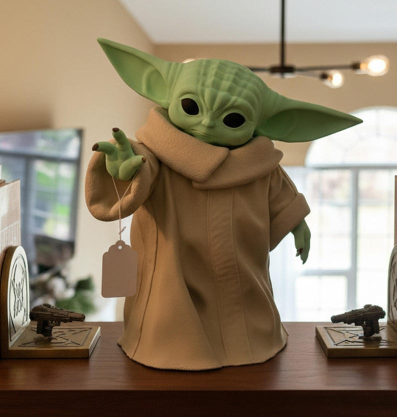 May include: A green figurine of a character from a popular science fiction franchise, wearing a tan robe and holding a blank tag. The figurine has large ears and black eyes. Two bookends with gun-shaped designs flank the figurine.