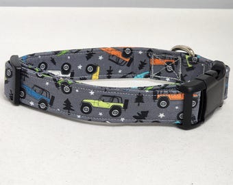 May include: A gray dog collar with a colorful print of cartoon off-road vehicles and trees. The collar has a black plastic buckle.