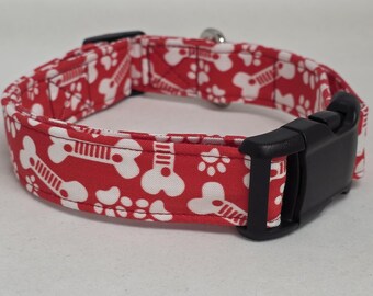May include: Red dog collar with a white bone and paw print pattern. The collar has a black plastic buckle.
