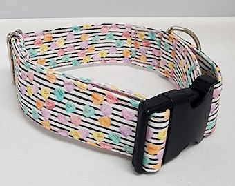 May include: A white dog collar with a black and white striped pattern and colorful candy hearts. The collar has a black plastic buckle.
