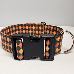 May include: A black and orange checkered dog collar with a black plastic buckle and a silver D-ring.
