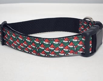May include: A black dog collar with a green and red pattern of Santa hats. The collar has a black plastic buckle.