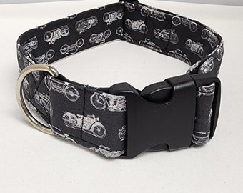 May include: Black dog collar with a white print of vintage motorcycles. The collar has a silver D-ring and a black plastic buckle.