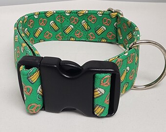 May include: A green dog collar with a black buckle and a silver D-ring. The collar has a repeating pattern of beer mugs and pretzels.