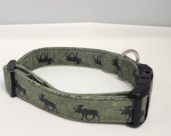 May include: A green dog collar with a black buckle and a silver ring. The collar has a repeating pattern of black moose silhouettes.