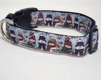 May include: A blue and white dog collar with a snowman pattern. The collar has a black buckle and a silver D-ring.