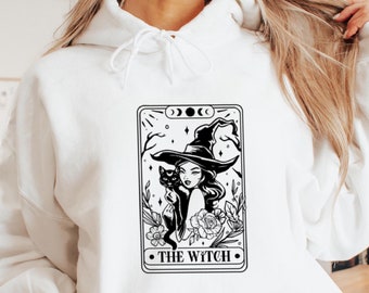 May include: White hoodie with a black and white illustration of a witch holding a black cat. The illustration is in the style of a tarot card and says "THE WITCH" at the bottom.