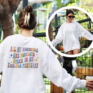 May include: White sweatshirt with the text "All my mornings are mondays stuck in an endless february" in rainbow colors on the back.