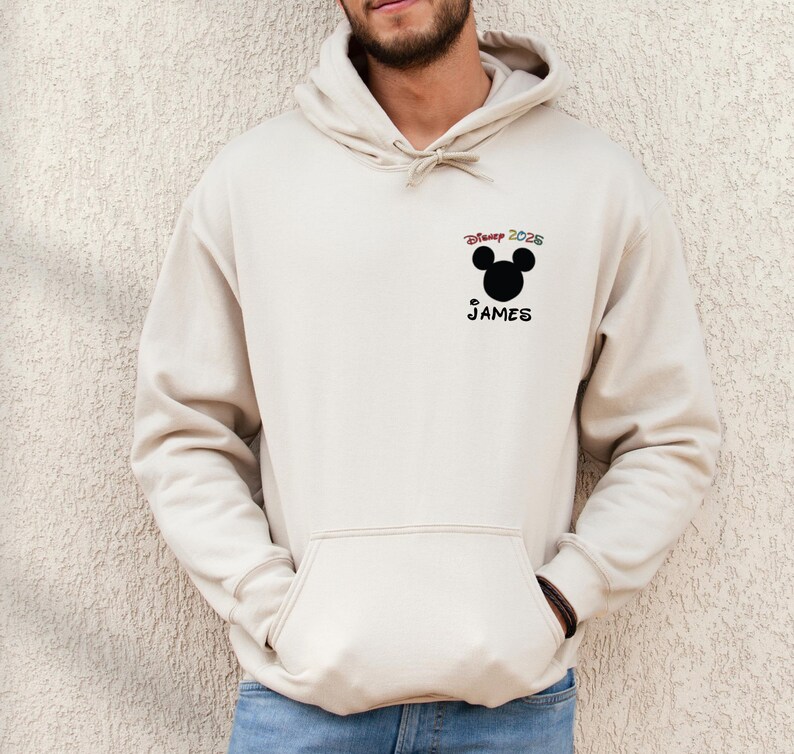 May include: A beige hoodie with a black Mickey Mouse head and the text "Disney 2025" above the head and "JAMES" below the head.