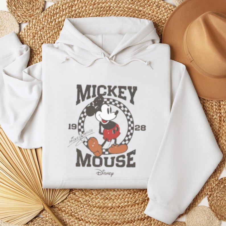 May include: White hooded sweatshirt with a vintage Mickey Mouse graphic. The graphic features Mickey Mouse in a red and black outfit, standing in a circle with the text "Mickey Mouse" and "1928" printed around him.