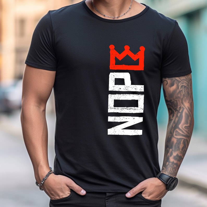 May include: Black t-shirt with a red crown graphic above the word "NDP" in white, vertically aligned. The shirt has short sleeves and a crew neck. The design is distressed, giving it a vintage look.
