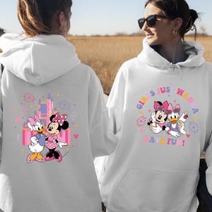 K&ouml;nnte beinhalten: Wei&szlig;er Kapuzenpullover mit einem farbenfrohen Aufdruck von Minnie Mouse und Daisy Duck. Auf der Vorderseite des Sweatshirts steht der Text "GIRLS JUST WANNA HAVE FUN!". Auf der R&uuml;ckseite des Sweatshirts befindet sich eine Schlossgrafik.