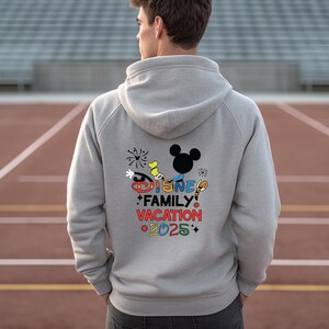 May include: Gray hooded sweatshirt with a colorful Disney Family Vacation 2025 graphic on the back. The graphic includes Mickey Mouse, fireworks, and other Disney characters.