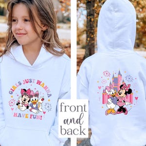K&ouml;nnte beinhalten: Wei&szlig;er Kapuzenpullover mit Minnie Mouse- und Daisy Duck-Grafiken. Auf der Vorderseite steht der Text "GIRLS JUST HANNA HAVE FUN!" mit farbenfrohen Akzenten. Auf der R&uuml;ckseite sind ein Schloss und die beiden Charaktere abgebildet.