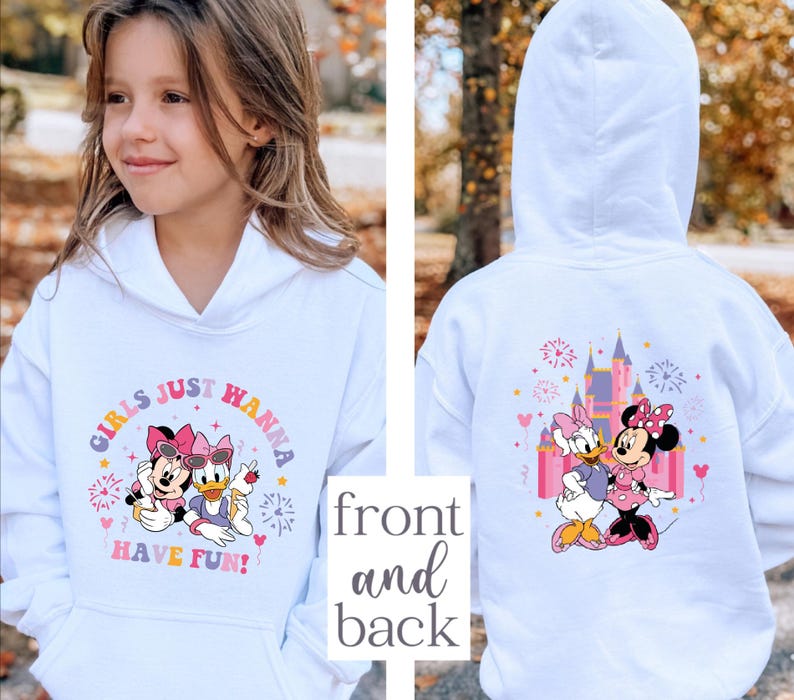K&ouml;nnte beinhalten: Wei&szlig;er Kapuzenpullover mit Minnie Mouse- und Daisy Duck-Grafiken. Auf der Vorderseite steht der Text "GIRLS JUST HANNA HAVE FUN!" mit farbenfrohen Akzenten. Auf der R&uuml;ckseite sind ein Schloss und die beiden Charaktere abgebildet.