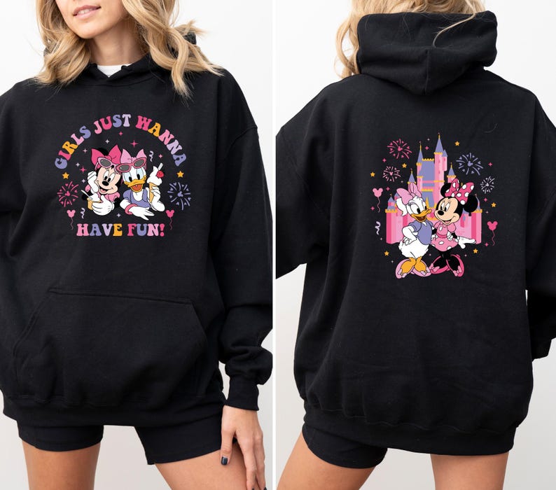 K&ouml;nnte beinhalten: Schwarzer Kapuzenpullover mit Minnie Mouse und Daisy Duck. Auf der Vorderseite steht "Girls Just Wanna Have Fun!" mit den Figuren. Auf der R&uuml;ckseite sind die Figuren vor einem Schloss mit Feuerwerk zu sehen.