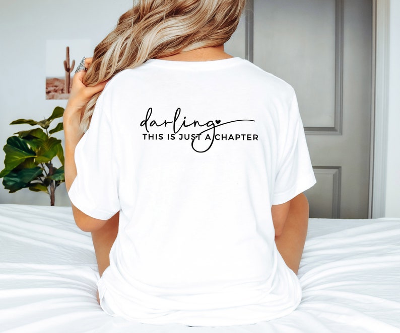 May include: White t-shirt with black text that reads "darling, this is just a chapter" with a small heart symbol.