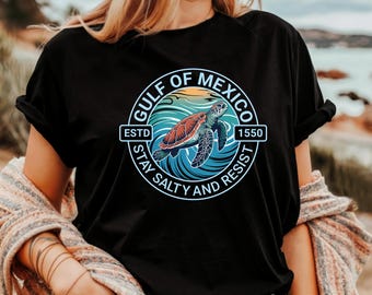 May include: Black t-shirt with a circular graphic of a sea turtle swimming in blue water with the text "Gulf of Mexico Est. 1550 Stay Salty and Resist".