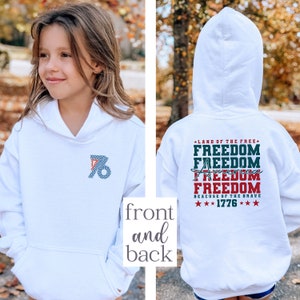 May include: White hooded sweatshirt with a red, white and blue graphic on the back that says "Land of the Free" and "Freedom" four times, with "America" in between the second and third "Freedom". The graphic also includes "Because of the Brave" and "1776". The front of the sweatshirt has a blue and white graphic of the number "76" with polka dots.