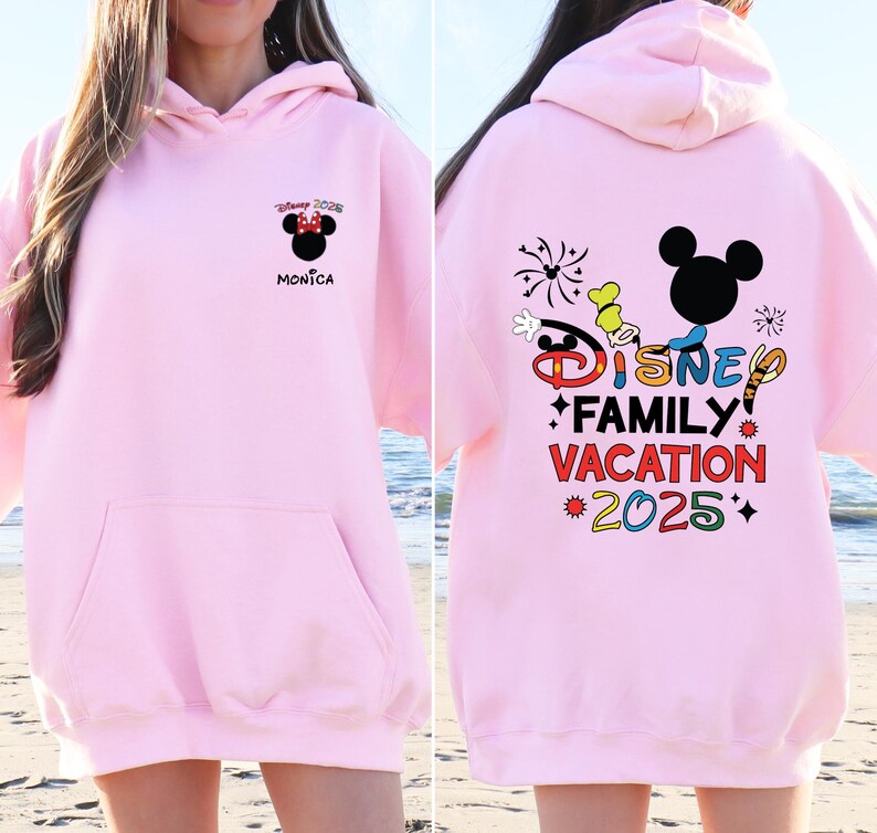 May include: Pink Disney Family Vacation 2025 hoodie with a Mickey Mouse graphic and fireworks. The front of the hoodie has a smaller Mickey Mouse graphic with the text "Disney 2025" and "Monica".