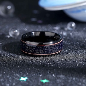 May include: A black tungsten carbide ring with a copper inlay and a blue glitter finish.