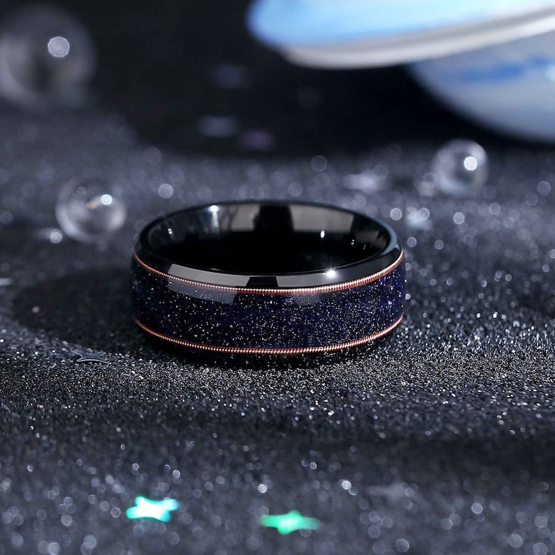 May include: A black tungsten carbide ring with a copper inlay and a blue glitter finish.