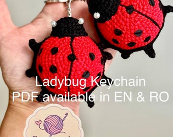 Puede incluir: Dos llaveros de mariquita hechos a mano con ganchillo. Las mariquitas son rojas con lunares negros y cabezas negras. Los llaveros están sujetos a anillos de metal plateado. La imagen también incluye el texto "Ladybug Keychain" y "Crochet Art".
