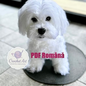 May include: A white crocheted Maltese dog sitting on a black round mat. The dog is looking at the camera. The text "PDF Română" is visible in the image. The text "Crochet Art" is also visible in the image.
