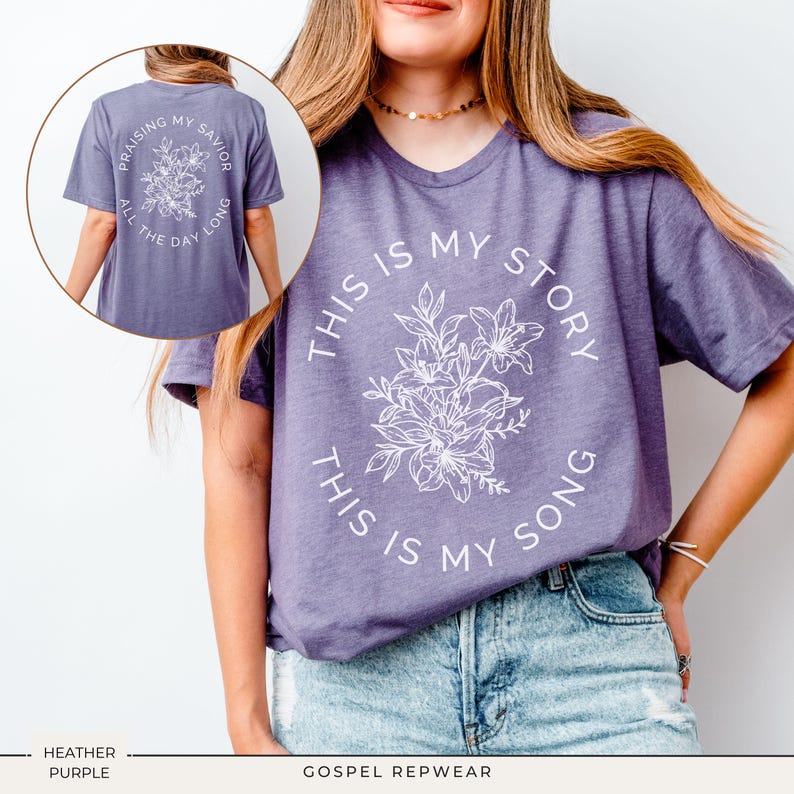 May include: Heather purple t-shirt with the text "THIS IS MY STORY, THIS IS MY SONG" in a circular design around a floral graphic. The back of the shirt has the text "PRAISING MY SAVIOR ALL THE DAY LONG" in a circular design around a floral graphic.