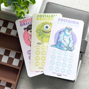 Puede incluir: Tres tarjetas de ahorro "Nostalgia Challenge" con personajes de dibujos animados. Cada tarjeta tiene un personaje diferente y una serie de círculos para rastrear los ahorros. El total ahorrado es de 140 €.