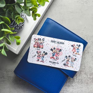 Op de afbeelding: Een blauwe leren portemonnee met een Disney Vacation spaartrackerkaart. De kaart bevat illustraties van Mickey en Minnie Mouse in verschillende outfits. De tekst "DISNEY VACATION" en spaarbedragen zijn zichtbaar.