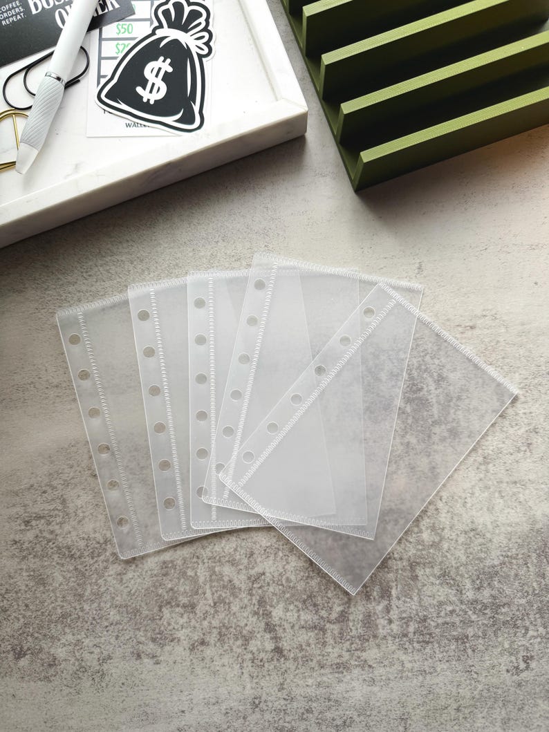 May include: Five clear plastic sheet protectors with six holes punched along the top edge. The protectors are designed for use in a binder or planner.