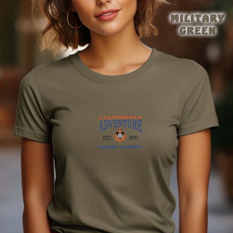 May include: A green t-shirt with the text "CALIFORNIA ADVENTURE EST. 2001 ANAHEIM, CALIFORNIA" and a Mickey Mouse head with a sunburst behind it.