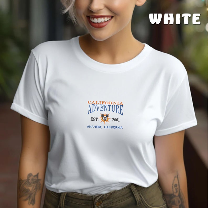 May include: White t-shirt with a blue and orange graphic that says "California Adventure Est. 2001 Anaheim, California" with a Mickey Mouse head inside a sun.