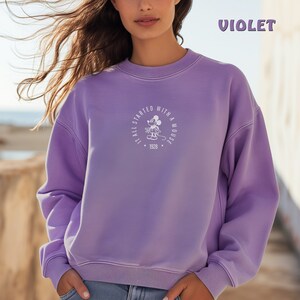 May include: A purple sweatshirt with a white graphic of Mickey Mouse in a circle with the text "It all started with a mouse. 1928."