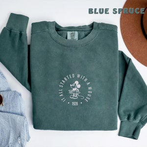 May include: A dark green sweatshirt with a white graphic of Mickey Mouse and the text "It all started with a mouse. 1928."