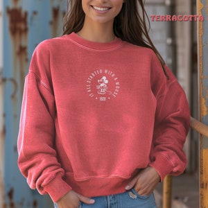 May include: A red sweatshirt with a white graphic of Mickey Mouse and the text "It all started with a mouse. 1928."