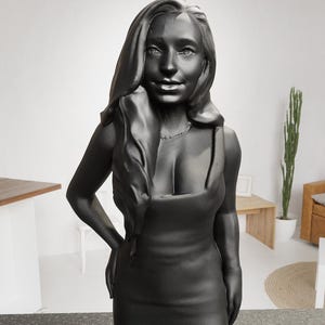 May include: A black 3D printed bust of a person with long hair wearing a black sleeveless dress.