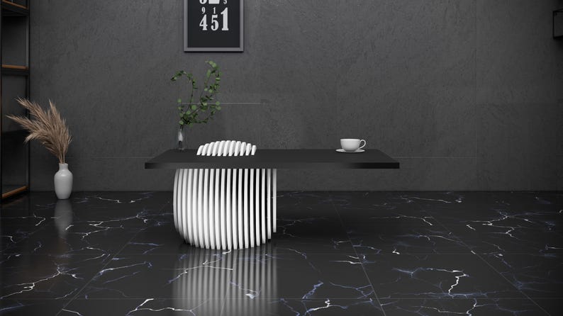 May include: A black and white modern desk with a white cup and saucer on the surface. The desk is in a room with a black marble floor and a gray wall. There is a plant in a vase on the left side of the image.