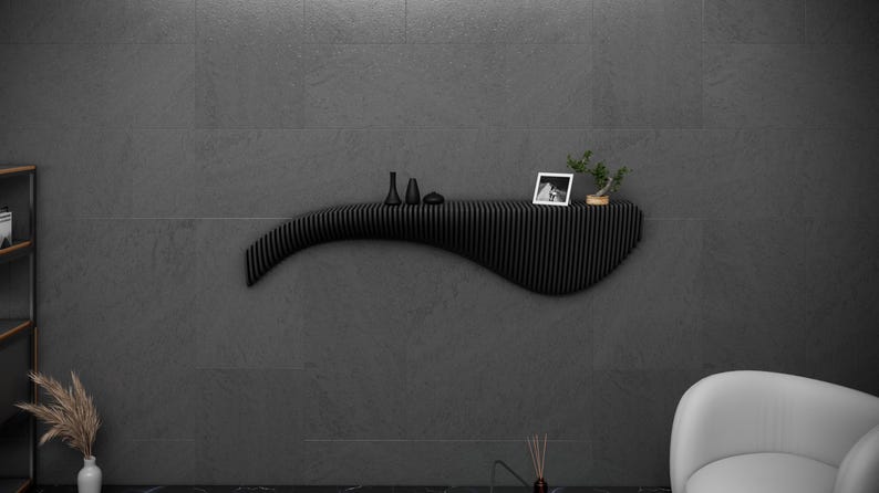 May include: A black, wavy, wall-mounted shelf with a picture frame, small decorative objects, and a small potted plant on top.