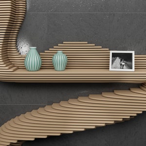 May include: A curved wooden shelf with a unique design, featuring two teal striped vases and a black and white photo frame. The shelf is mounted on a gray wall.