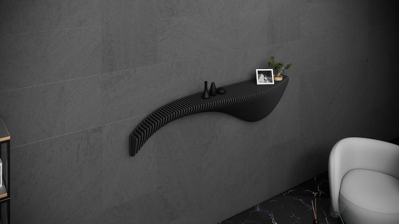 May include: A black, curved wall shelf with a slatted design. The shelf has a small plant, two black decorative items, and a framed photo on it.