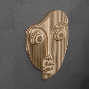May include: A wooden wall sculpture of a face with closed eyes and a slightly parted mouth. The sculpture is made of thin strips of wood that are layered to create a 3D effect.
