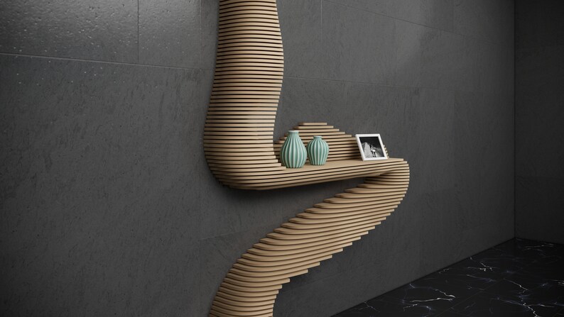 May include: A wooden wall shelf with a unique curved design. The shelf has two small teal vases and a framed black and white photo on it.