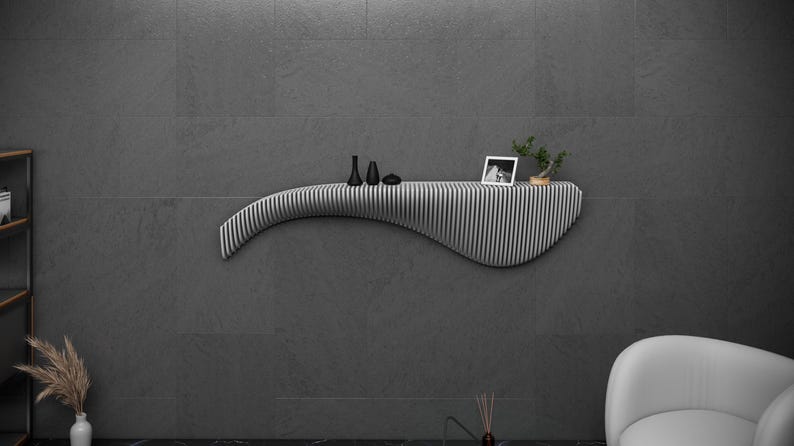 May include: A white, curved, wall-mounted shelf with black and white vertical stripes. The shelf has a small black and white photo, two black vases, and a small potted plant on top.