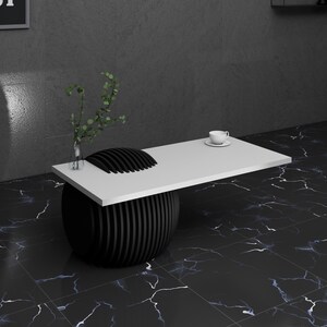May include: A white table top with a black, round, ribbed base sits on a black and white marble floor. A small white cup and saucer are on the table top.