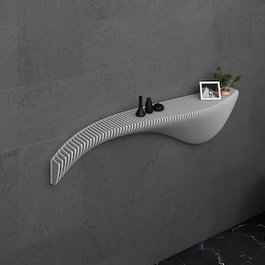 May include: A white, curved, wall-mounted shelf with a slatted design. The shelf has a few small objects on it, including a picture frame and a small plant.