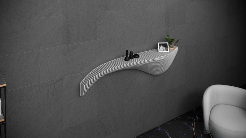 May include: A white, curved, wall-mounted shelf with a slatted design. The shelf has a few small objects on it, including a picture frame and a small plant.