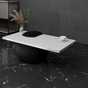 May include: A white table top with a black, round, segmented base. The table is on a black and white marble floor. A white cup and saucer are on the table.