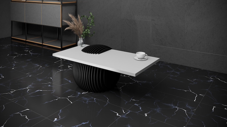 May include: A white table top with a black, round, segmented base. The table is on a black and white marble floor. A white cup and saucer are on the table.